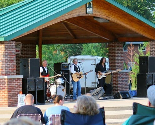 Spectators sitting in lawn chairs as they listen to a band performing at the Beech Acres Park Amphitheater