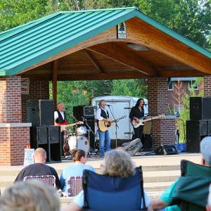 Spectators sitting in lawn chairs as they listen to a band performing at the Beech Acres Park Amphitheater