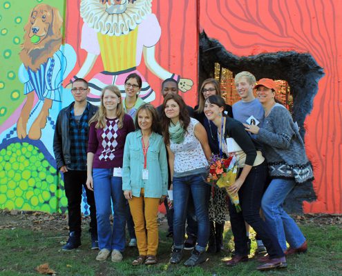 Team poses for a photo in front of the Kellogg Park Dog Field mural by Artworks