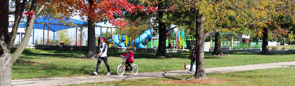park patrons walking on the trail at juilfs park. Playground is in the background