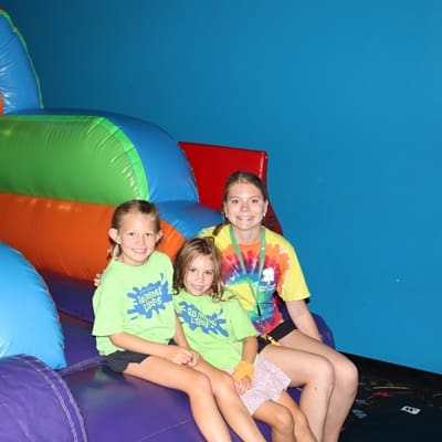 A summer camp counselor and two campers taking a break while enjoying playing on inflatables at a field trip
